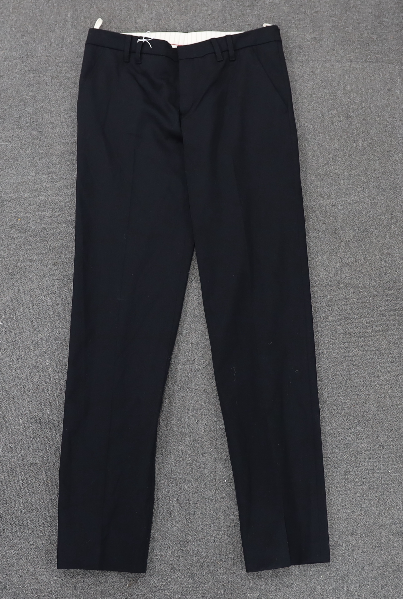 A Prada black A line wool skirt with silver embellishment on the pockets, a blue cotton canvas short swing raincoat and a black pair of wool suit trousers, all size 42